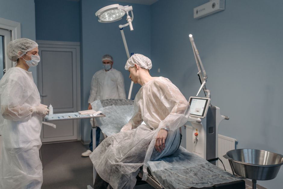 A medical team in sterile gowns prepares for a clinical procedure in a well-equipped room.