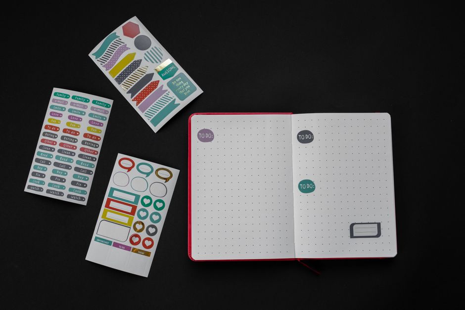Open notebook with colorful stickers arranged creatively on a black background.