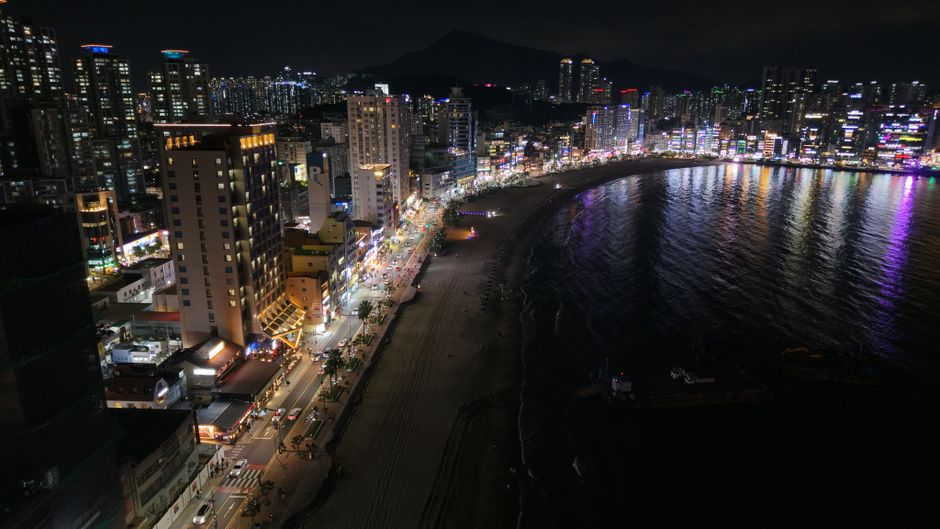 Stunning night view of Busan's skyline and beach, showcasing vibrant city lights.