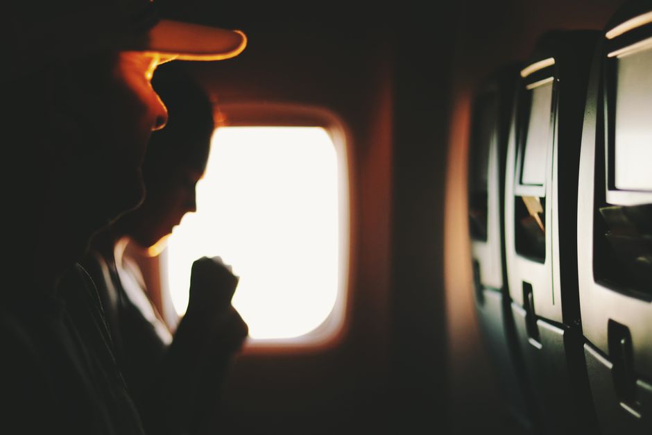 Silhouetted passengers sitting by a window during a flight, capturing a serene travel moment.