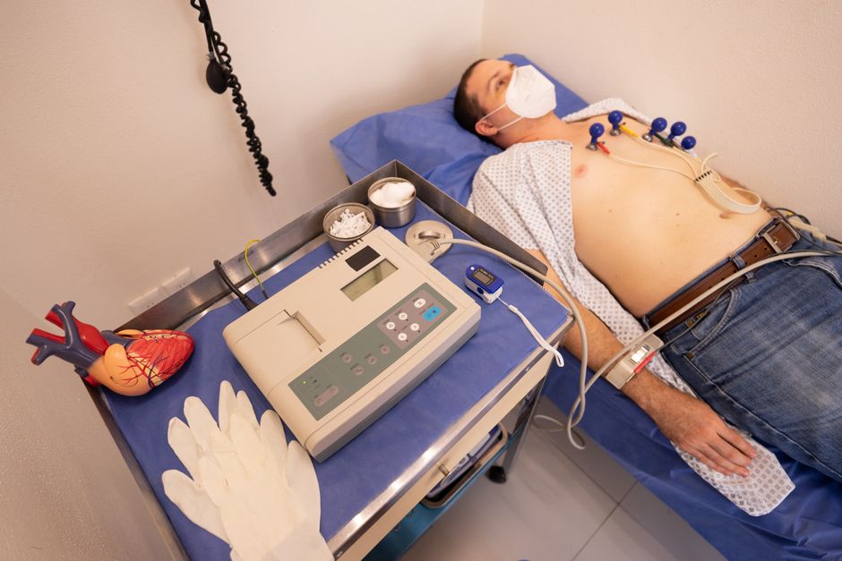 A man undergoing a cardiology exam with an ECG machine in a medical clinic.