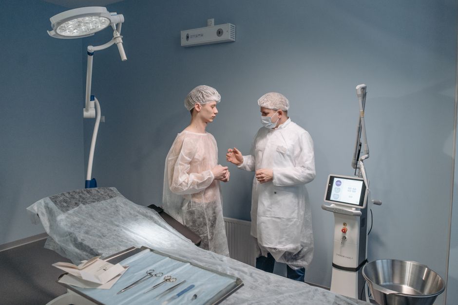 Patient lies on surgical table as medical professional adjusts protective eyewear.