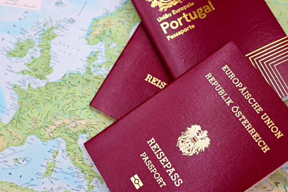 Close-up of European passports from Portugal and Austria on a world map.