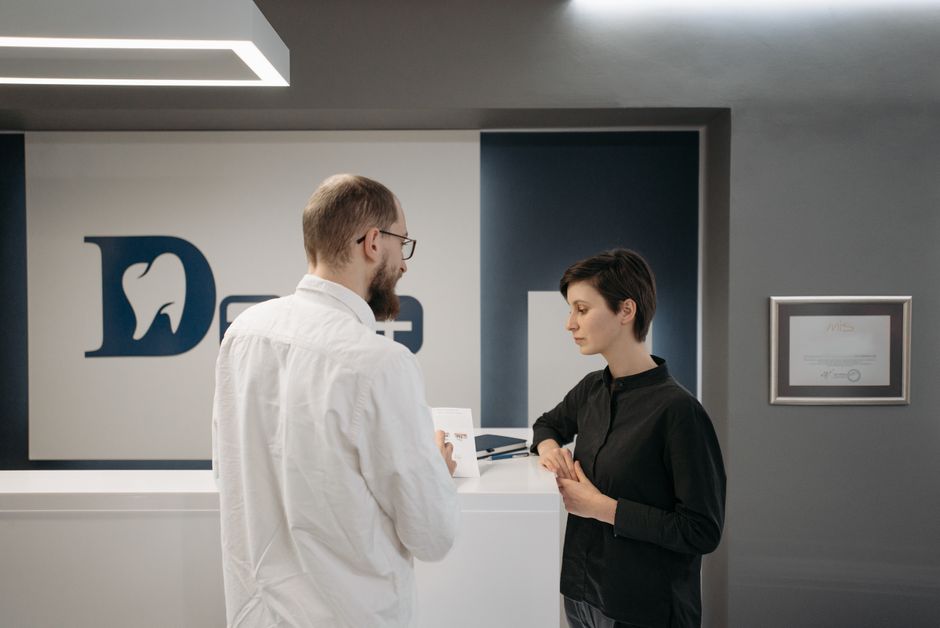 A male dentist consulting a female patient at a modern dental clinic reception.